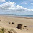 An image of Fraisthorpe beach, looking north towards Bridlington, where still there are reminders of the Second World War, with abandoned concrete pill boxes and anti-tank blocks placed among the sand dunes