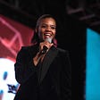 Candace Owens, black conservative activist, smiling and talking into a microphone.