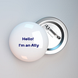 A white pin badge with the words “Hello! I’m an Ally” in dark blue, on a grey background.