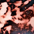 Close-up photo of black denim stained with spattered bleach.
