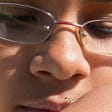 close up of young face with glasses looking at tiny preying mantis