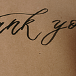 A person writing Thank You on a card