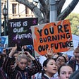Young people protesting with signs that read “this is our future” and “you’re burning our future”