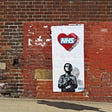 Artwork on a brick wall showing a boy looking up at a heart containing the NHS logo