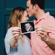 couple stands together embracing with photo of fetus in hand, oogenesis