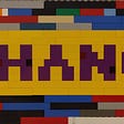 Sign made of multicolored Lego bricks with the word CHANGE in purple on a yellow background.