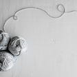 Three grey yarn balls on a light grey background