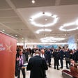 A photograph of people networking at an NLC event, with a banner in the foreground saying “National Leadership Centre”