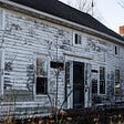 Dilapidated house with faded paint on the siding