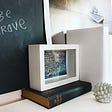 Be Brave written on a blackboard with books on a shelf
