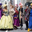 A group of older women wearing colorful, maximalist outfits in many colors and patterns with radiant expressions.