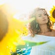 Woman in white off shoulder top among sunflowers