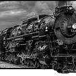An old black and white locomotive train coming down the tracks