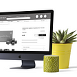 A mock up of the Fresh Crop Website on a Mac, with a plant and candle beside the screen.