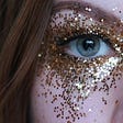 Closeup of woman’s eye with glitter on her face.