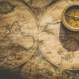 Old maps of the world with a sepia tint and an old compass