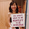 Tiffany is holding a sign that reads “You don’t have to be perfect to be amazing” at the 2019 California Miss Amazing pageant
