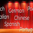 A stage with a lit red curtain and various languages typed across it.