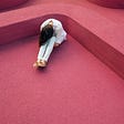 Lonely person with head down on knees in abstract red environment