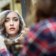 A woman looks at herself in the mirror