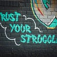 “Trust Your Struggle” written in graffiti on a brick wall.