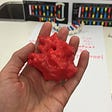 A hand holding a 3D printed model of RNA polymerase.