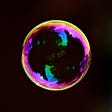 A perfectly formed bubble, reflecting purple and green colours off its shiny surface, floats in the black sky