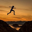 Woman leaping across gap at sunset