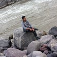 Me sitting on a rock beside a flowing river