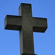 large stone cross across a blue sky background