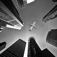IMAGE: An airplane on flying on top of a few skyscrapers, seen from the ground