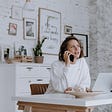Woman talks on the phone working from a home environment.