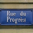 A French street sign that means “Progress Street” on a building.
