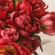 A photo of a red flower bouquet on an off-white background