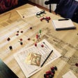 A picture a Dungeons and Dragons game session. There are dice, game markers and map on a table.