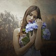 Woman with a sad expression hugging a bouquet of blue flowers