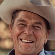 Close-up of Ronald Reagan’s face. He is smiling and wearing a cowboy hat.