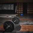 a loaded barbell lays in an empty gym with moody lighting