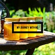Outside Photo of jars of honey on at table. A single honey bee flying in the background.