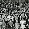 an auditorium full of people in creepy masks
