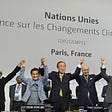 World leaders raise their hands in celebration after signing the Paris Climate Agreement.