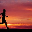 Male runner silhouetted against fiery horizon