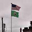 Photo of 2 flags on flag pole top is American Flag and lower Flag of George Washington
