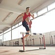 Athletic man jumping over hurdle