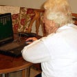 old lady playing solitaire on black laptop
