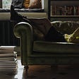 Person Lying Down on Sofa Reading a Book