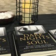 Book on table with black tablecloth in front of candle