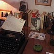 An image of a typewriter on a desk with Russian novels and documents stacked upon it