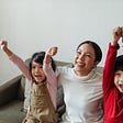 Happy Asian woman with kids cheering while watching TV