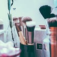 A close up camera shot of a variety of beauty products like brushes, cotton balls, and q-tips